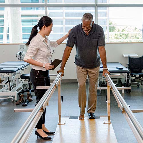 A physical therapist helps a patient walk