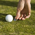 Detail of a golfer marking the ball's position with a coin.