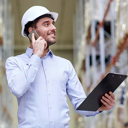 A worker holds a tablet and phone