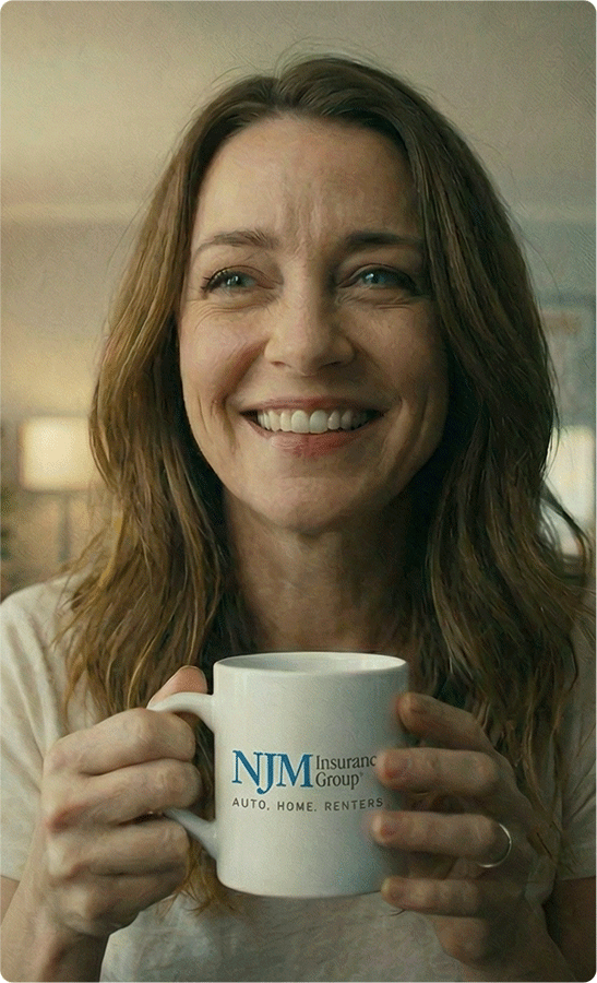 Woman smiling while holding a NJM Insurance mug.
