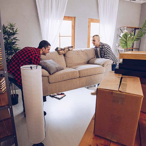 Two men move furniture into a home