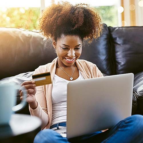 A woman holds a credit card and looks at her computer