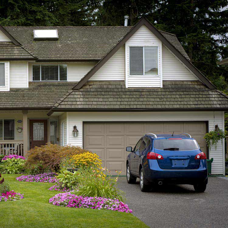 A blue car parked in front of a home